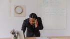 Man with braided hair leaning over desk while talking on the phone [Image credit: RDNE]