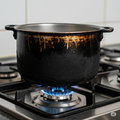 A sufuria with soot on a gas burner