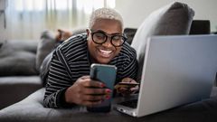 A woman using her phone while lying on the couch