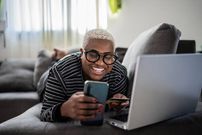A woman using her phone while lying on the couch