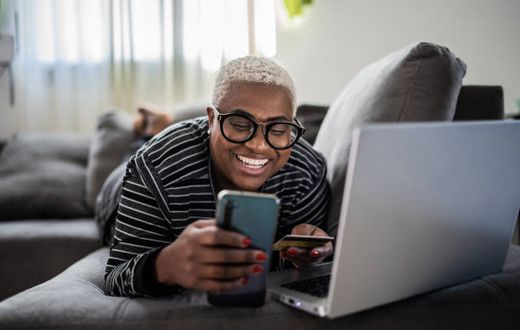 A woman using her phone while lying on the couch