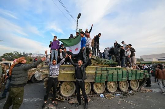 People celebrate with anti-government fighters at Umayyad Square in Damascus on December 8, 2024