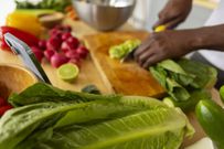 A person preparing vegetables while checking his for a recipe