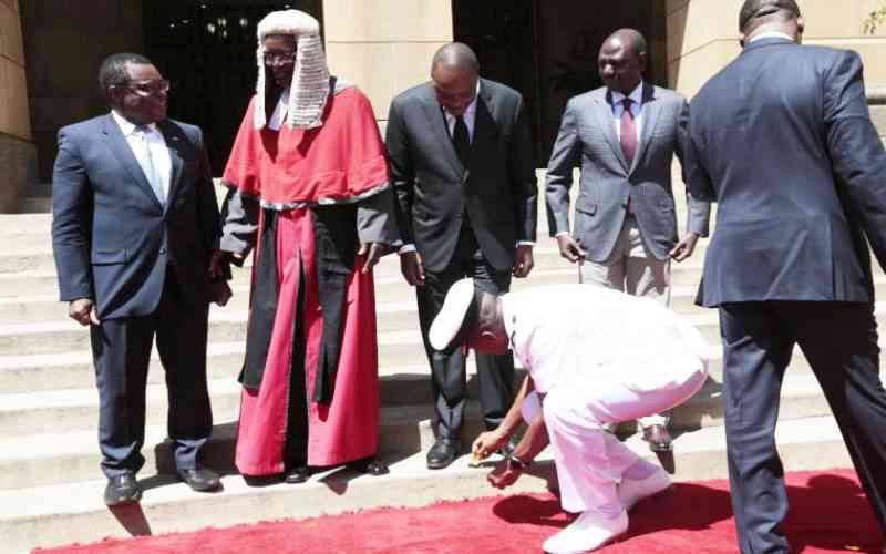 Former Aide-de-Camp Major General Timothy Stelu Lekolool pictured wiping former President Uhuru Kenyatta's shoes