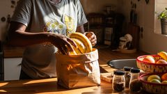 A lady taking ripe bananas off a paper bag