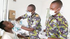 A Kenya Defence Forces specialist officer (middle) offers dental services to a civilian