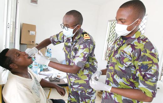 A Kenya Defence Forces specialist officer (middle) offers dental services to a civilian