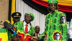 Former Zimbabwean President Robert Mugabe shakes hands with his son, Robert Mugabe Jr., who pleaded guilty to drug possession on November 13, 2025