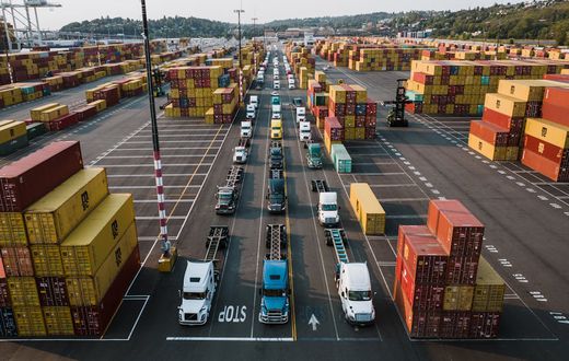 Parked trucks and cargo containers in a port [Image Creidt: Kelly]
