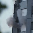 An arm holding a cloth can be seen waving from a window of Grenfell Tower as smoke rises from a lower window