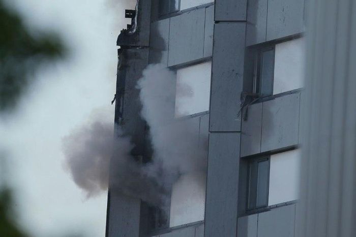 An arm holding a cloth can be seen waving from a window of Grenfell Tower as smoke rises from a lower window