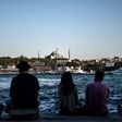People sit on the docks of the Karakoy district, across from the Hagia Sophia former mosque, enjoying the attractions of Istanbul