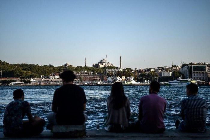 People sit on the docks of the Karakoy district, across from the Hagia Sophia former mosque, enjoying the attractions of Istanbul