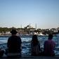 People sit on the docks of the Karakoy district, across from the Hagia Sophia former mosque, enjoying the attractions of Istanbul