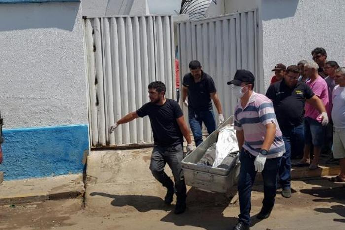 Forensic experts carry a corpse to be transported to the morgue after an attempted bank robbery in Milagres, Ceara state, Brazil