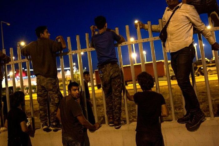 Migrants try to jump over a fence into a ferry terminal in Patras, southwestern Greece, on June 20, 2017