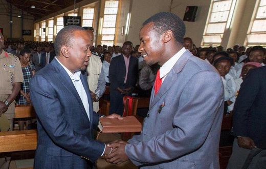President Uhuru Kenyatta receives a Bible on Fathers' Day, from Kimende boda boda rider Destiny Gitau, at St Peter and Paul Catholic Church in Kiambu town, June 18, 2017.