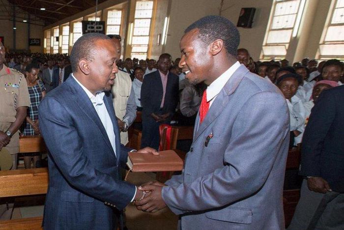 President Uhuru Kenyatta receives a Bible on Fathers' Day, from Kimende boda boda rider Destiny Gitau, at St Peter and Paul Catholic Church in Kiambu town, June 18, 2017.