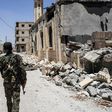 A member of the Syrian Democratic Forces (SDF), an alliance of Kurdish and Arab fighters, walks on a damaged street in western Raqa