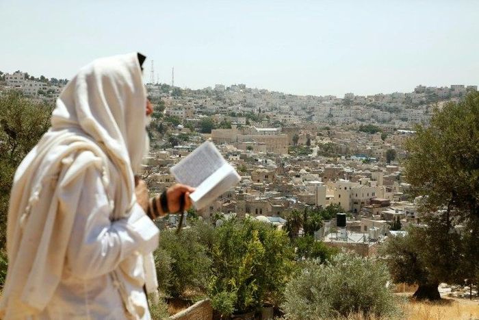 An Israeli settler stands on Palestinian land overlooking the Ibrahimi Mosque and the old city of the West Bank town of Hebron