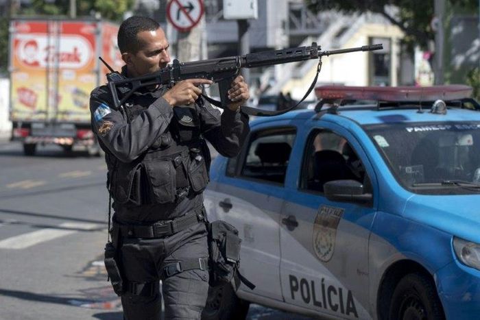 A militarized police officer aims his assault rifle during a search and capture operation at the Mangueira shanty town in Rio de Janeiro, after a policeman there was shot dead