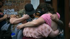 Mourners embrace next to a makeshift memorial to Heather Heyer in Charlottesville, Virginia, on the one year anniversary of her death at the hands of a white supremacist in a speeding car