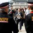 Police officers stand on duty as commuters walk across London Bridge in London on June 5, 2017, after it was partially re-opened following the June 3 terror attack