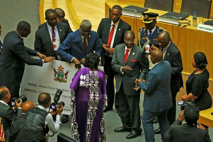Zimbabwe's President Robert Mugabe, center, gives a $1 million cheque to the African Union during a summit meeting in Addis Ababa, Ethiopia