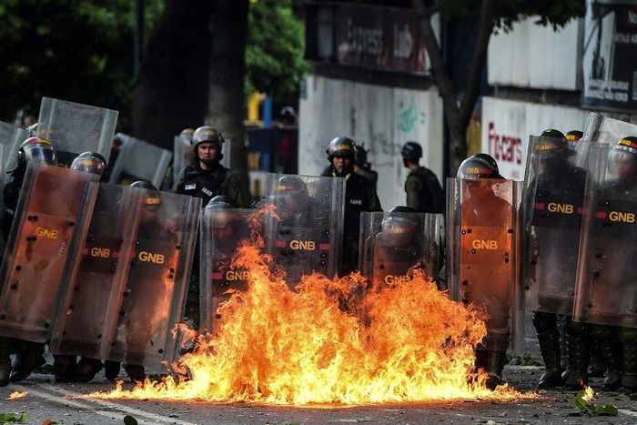 Members of Venezuela's National Guard use their shields to form a barrier from a fire during clashes with anti-government demonstrators in Caracas
