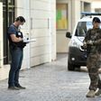 An armed French soldier patrols next to a forensic police officer near the site where a car slammed into soldiers in Levallois-Perret, outside Paris, on August 9, 2017