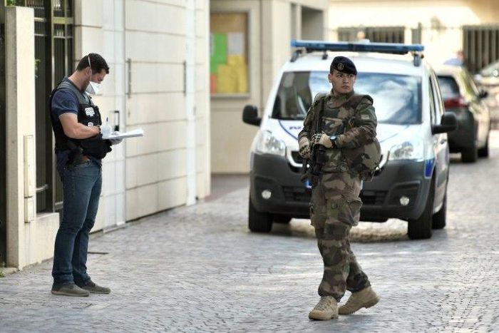 An armed French soldier patrols next to a forensic police officer near the site where a car slammed into soldiers in Levallois-Perret, outside Paris, on August 9, 2017
