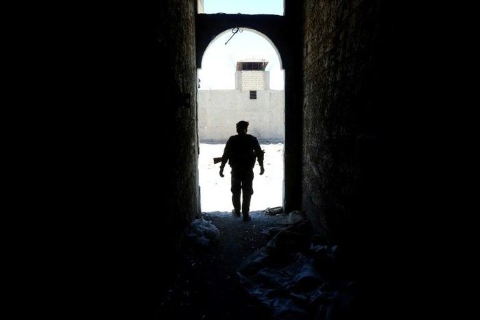 A member of the Syrian Democratic Forces (SDF) walks out of a building on June 27, 2017 on the western city limits of Raqa after the area was seized from the Islamic State group