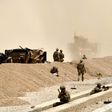 US soldiers keep watch near the wreckage of their vehicle at the site of a Taliban suicide attack in Kandahar on August 2, 2017