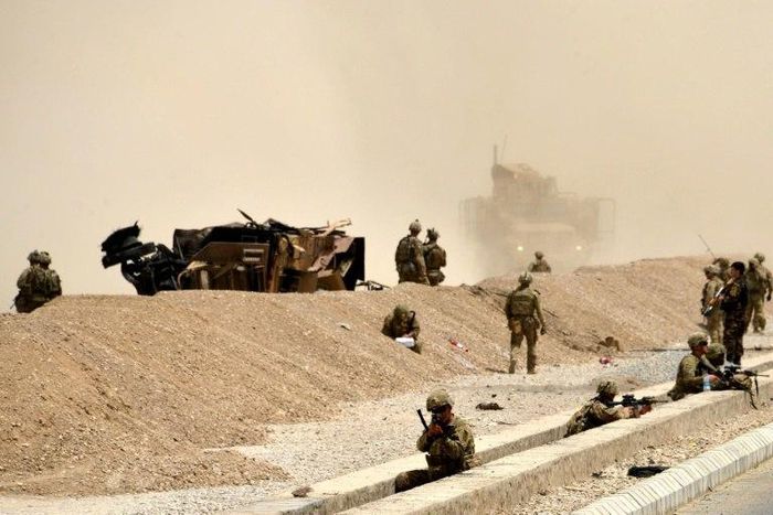 US soldiers keep watch near the wreckage of their vehicle at the site of a Taliban suicide attack in Kandahar on August 2, 2017