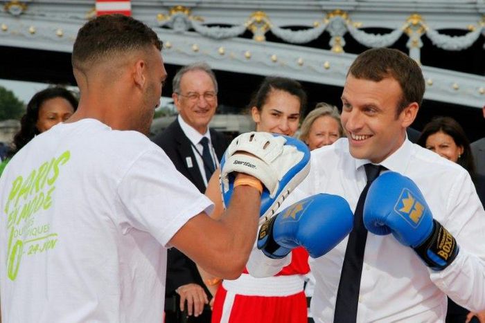 French President Emmanuel Macron (R) spars with a boxing partner on a barge floating on the river Seine in Paris in a bid to promote the candidacy of the city of Paris for the Summer Olympics Games in 2024