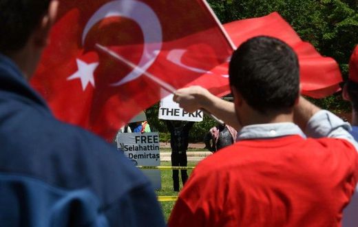 Pro-Erdogan supporters wave Turkish flags at anti-government protesters in front of the White House in Washington, DC on May 16, 2017