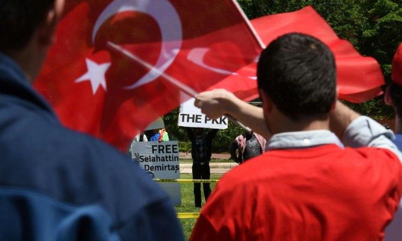 Pro-Erdogan supporters wave Turkish flags at anti-government protesters in front of the White House in Washington, DC on May 16, 2017