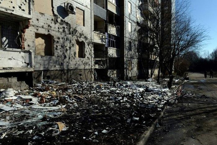 Pedestrians walk past a damaged building in Donetsk