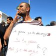 A protester in Tunis openly smokes a cigarette and holds a placard reading in French "Why does it bother you if you fast and I eat?" during Ramadan on June 11, 2017