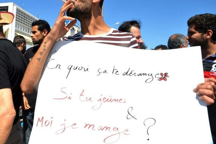 A protester in Tunis openly smokes a cigarette and holds a placard reading in French "Why does it bother you if you fast and I eat?" during Ramadan on June 11, 2017