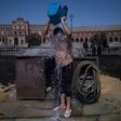 A man cools with a bucket of water next to Plaza de Espana in Seville during a heat wave, on July 13, 2017