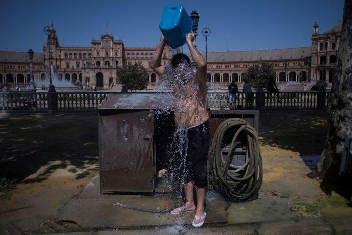 A man cools with a bucket of water next to Plaza de Espana in Seville during a heat wave, on July 13, 2017