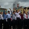 People gesture as coverage of an ICBM missile test is displayed on a screen in a public square in Pyongyang