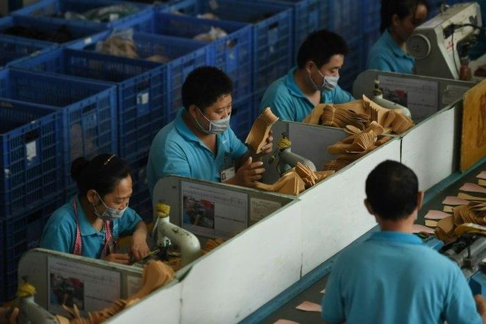 (FILES) This file photo taken on September 14, 2016 shows workers on a production line at the Huajian shoe factory in Dongguan