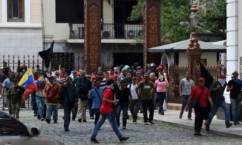 Stick-wielding supporters of Venezuelan President Nicolas Maduro broke through the front gate of the National Assembly building and set off fireworks in the interior gardens