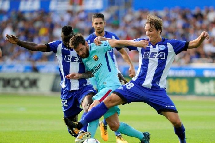 Barcelona's Lionel Messi (C) vies with Deportivo Alaves' Wakaso Mubarak (L) and Tomas Pina (R) during their match in Vitoria on August 26