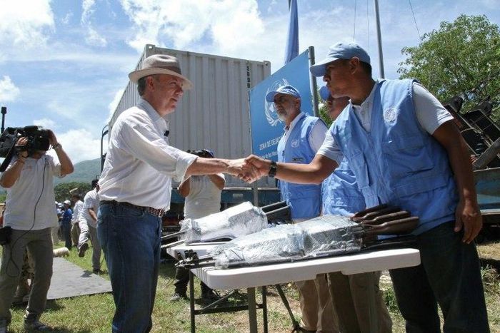 Colombian President Juan Manuel Santos shakes hands with a UN observer before closing the last container with weapons surrendered by the Revolutionary Armed Forces of Colombia (FARC) in a ceremony that brought the country's 50 year war to a final end