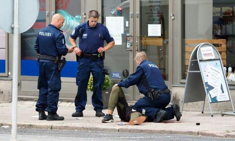 Police officers detain the Moroccan suspect who was shot in the leg, in the Finnish city of Turku after a stabbing spree that left two people dead.