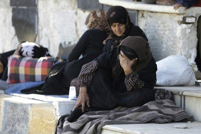 Displaced Syrians who fled areas controlled by the Islamic State with their families gather at Aleppo's Ramussa bus station on July 4, 2017