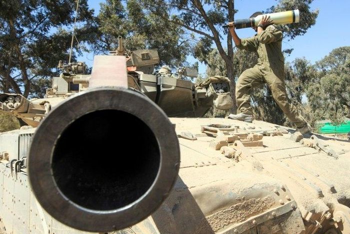 An Israeli soldier carries a shell as he and his comrades prepare their Merkava tanks stationed on the border between Israel and the Gaza Strip on July 31, 2014